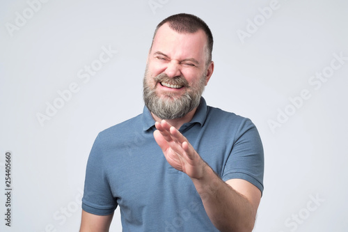 Laughing positive mature guy dressed in blue t-shirt showing stop gesture