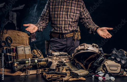 Man in a checkered shirt showing his military uniform and equipment. Modern special forces equipment.