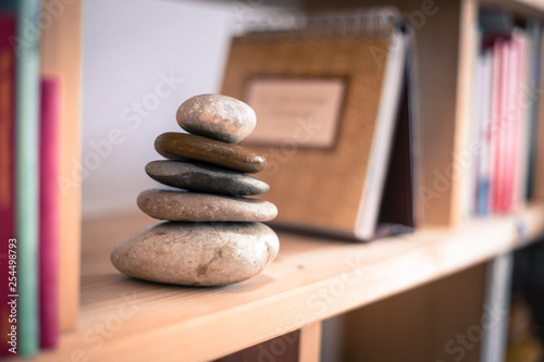 Feng Shui: Stone cairn in a book shelf in the living room, balance and relaxation