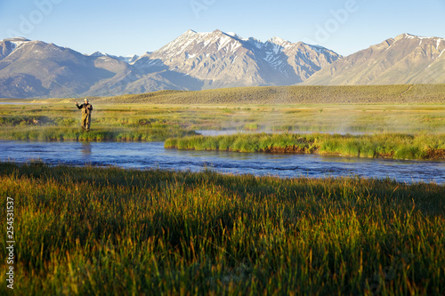One man fly fishing on the Owens River at sunrise with the Sierra Nevada Mountains in the distance