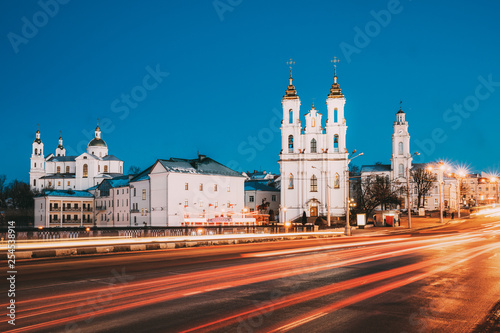 Vitebsk, Belarus. Traffic At Street And Holy Assumption Cathedral, Holy Resurrection Church And City Hall In Evening Or Night Illumination At Winter