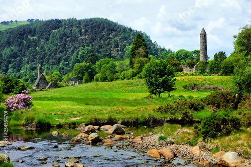 View of the historic Glendalough monastic site with ancient round tower and church in Wicklow National Park, Ireland