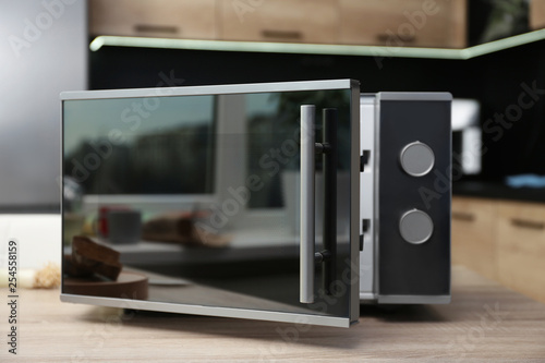 Open modern microwave oven on table in kitchen