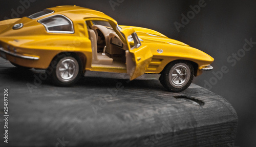 Toy car model Corvette Sting Ray 1963 year. Yellow color. Side view. Opened door. Close-up. Macro. Isolated.