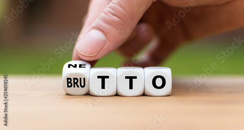 Hand dreht einen Würfel und ändert das Wort "Brutto" in "Netto".