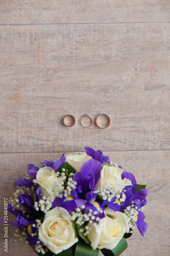 Bukiet ślubny z pierścionkiem zaręczynowym i obrączkami na parkiecie
