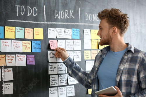 Young man near scrum task board in office