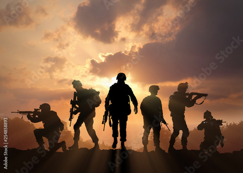 Six military silhouettes on sunset sky background