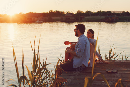 Young loving couple enjoys by the river during the sunset