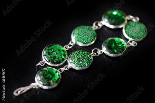 Resin bracelet with green sparkles on a dark background close up