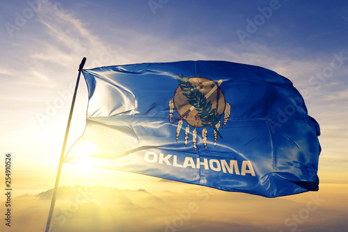 Oklahoma state of United States flag waving on the top sunrise mist fog