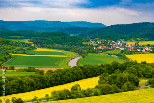 A great landscape view of the Werra Valley with the river Werra, cultivated fields, a railway bridge and the town Oberrieden; surrounded by forest and the low-mountain range of Hesse and Thuringia.