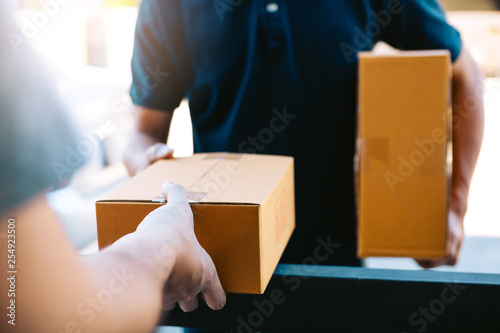 Close up of hands cargo staff are delivering cardboard boxes with parcels inside to the recipient's hand.