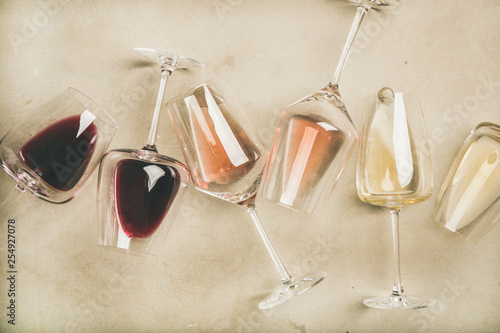 Flat-lay of red, rose and white wine in glasses over grey concrete background, top view. Wine bar, winery, wine degustation concept