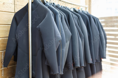 Black surfing wetsuits hanging on rack for rent in surf club