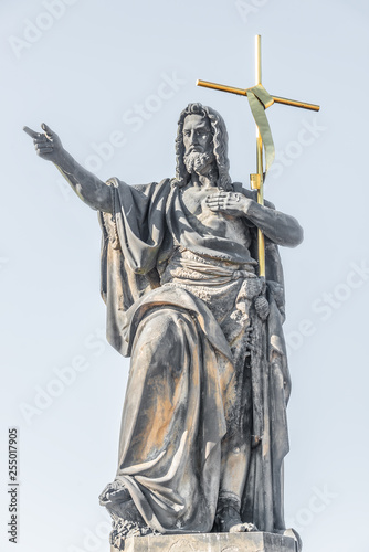 Statue of saint with cross at the Charles Bridge in Prague, Czech Republic, summer time