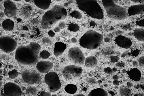 The holes on the porous sponge for washing dishes close up black and white