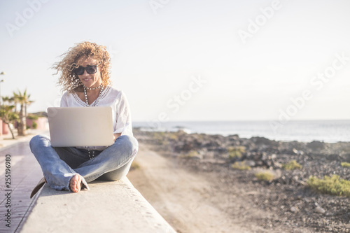 Technology and travel. Working outdoors. Freelance concept. Pretty young woman using laptop beach.