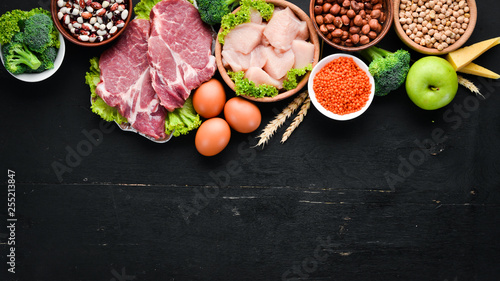 High protein food. Healthy nutrition or diet concept. Meat, chicken fillet, broccoli, beans, cheese, eggs, wheat. On a black background.