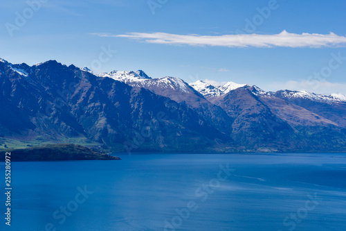 peaceful landscape during sunny day with calm sky above the lake and mountain range, perfect hiking area