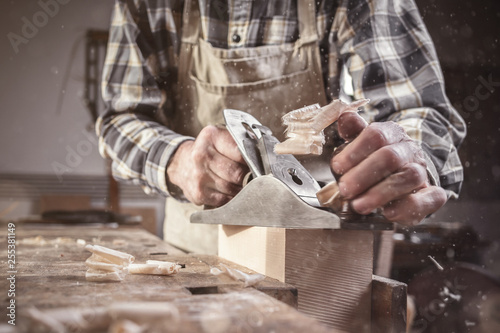 Hände eines Tischlers bei der Arbeit mit dem Hobel