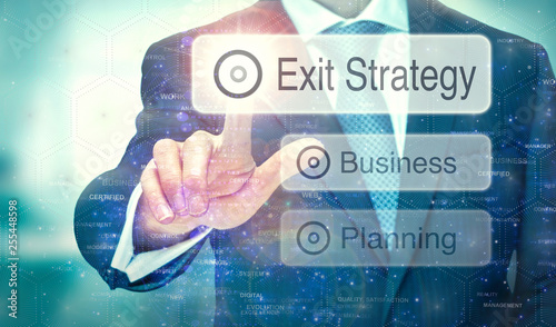 A business man selection a button on a futuristic display with a Exit Strategy concept written on it.