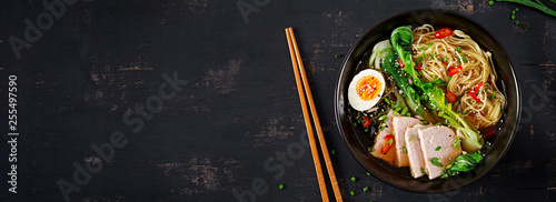 Miso Ramen Asian noodles with egg, pork and pak choi cabbage in bowl on dark background. Japanese cuisine. Top view. Banner