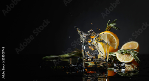 Cocktail gin-tonic with lemon slices and twigs of rosemary.