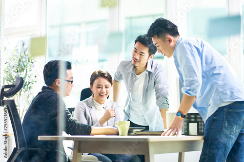 group of four asian teammates working together discussing business in office