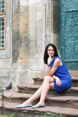 Young woman sitting on stairs of the old antique building.