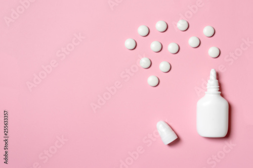White plastic nasal spray with tablets on pink background - sinusitis, geniantritis, rhinitis and other diseases of ENT organs concept