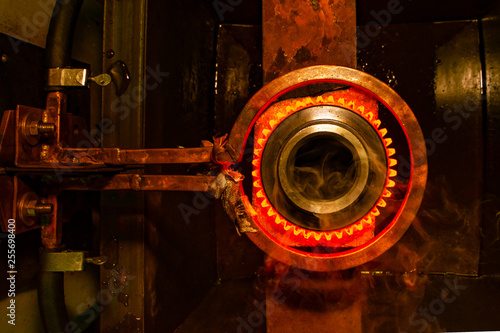 closeup calcining hot metal steel gear parts in a factory induction furnace with smoke