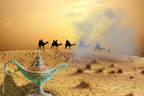 Magic genie lamp on sand dunes with camel ride caravan traveling in Arabian Desert