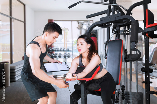 Young trainer helps his client to train in the gym