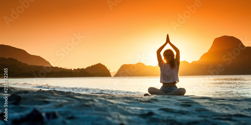 Silhouette of young girl doing yoga at sunset time
