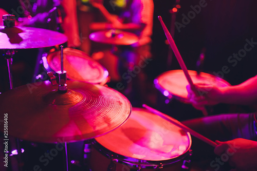 man plays musical percussion instrument with sticks closeup on a black background, a musical concept with the working drum, beautiful lighting on the stage.