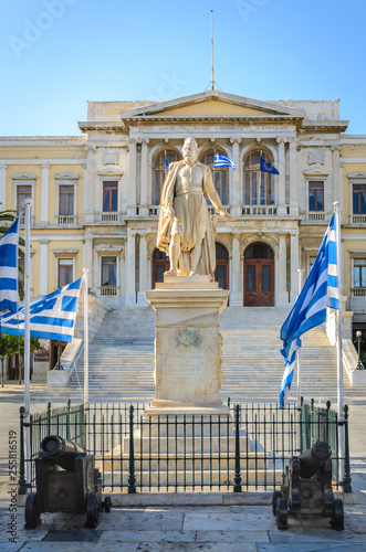 Miaoulis statue surrounded by greek flags in front of the townhall of Syros island in Cyclades Greece