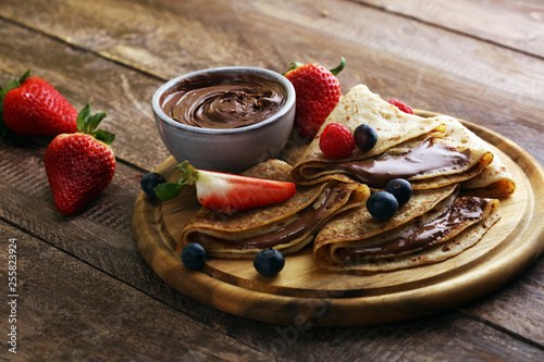 Delicious Tasty Homemade crepes with chocolate or pancakes with raspberries and blueberries on rustic wood