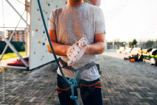 Young man wearing belay and sprinkling hands with talc
