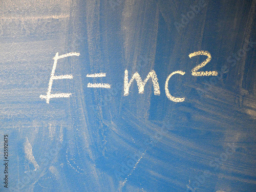 Mathematical formula e=mc2 squared written on a blue, relatively dirty chalkboard by chalk.