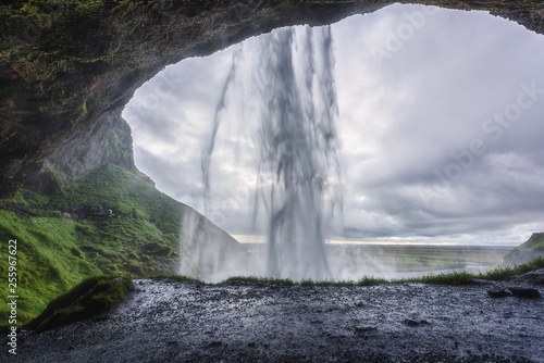 Beautiful Seljalandsfoss waterfall in nasty day, summer landscape, view from the small cave, popular tourist attraction in South Iceland, travel background