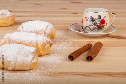 Rogaliki posypane cukrem oraz filiżanka na drewnianym stole