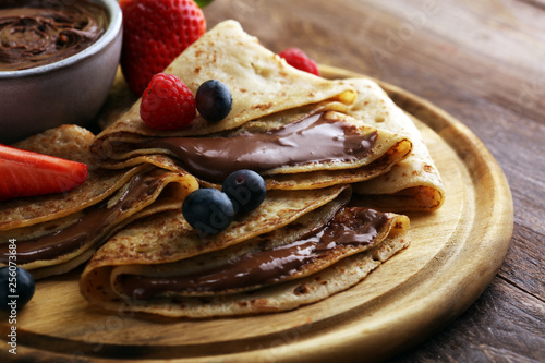 Delicious Tasty Homemade crepes with chocolate or pancakes with raspberries and blueberries on rustic wood