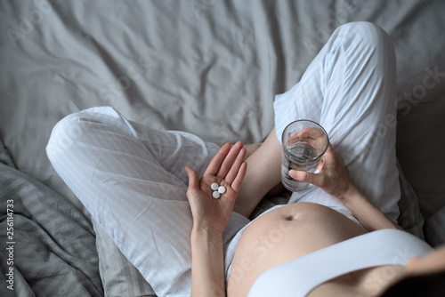 pregnant woman with pills and glass of water on her hands