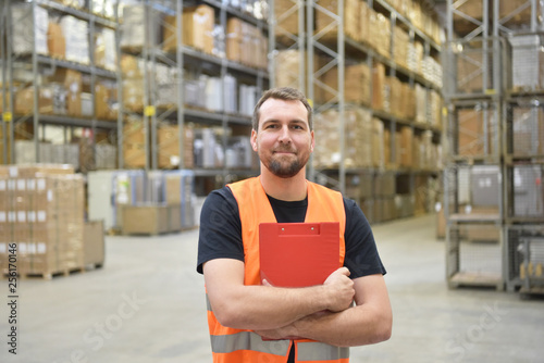 fröhlicher Logistikarbeiter in einer Lagerhalle - Interieur einer Industriehalle einer Spedition // happy logistics worker in a warehouse - interior of an industrial hall of a forwarding company 