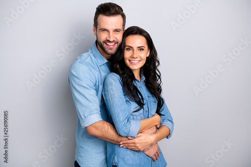 Joyful family. Portrait of isolated cute recently married people pregnant waiting for baby in warm sweet cuddles dressed in denim shirts over argent background