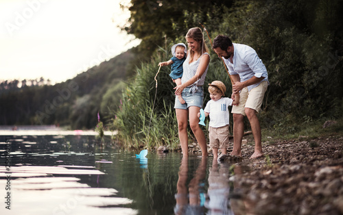 A young family with two toddler children outdoors by the river in summer.