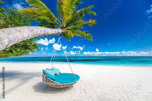 Tropical beach background as summer landscape with beach swing or hammock and white sand and calm sea for beach banner. Perfect beach scene vacation and summer holiday concept. Boost up color process