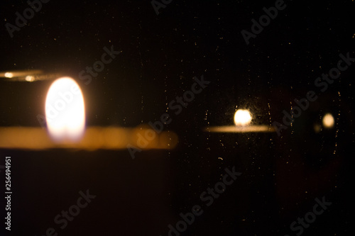 płomień świecy odbity w deszczowym oknie