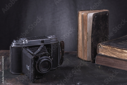 Zabytkowe, muzealne przedmioty na wystawie , ksiazki i analogowy aparat fotograficzna na klisze fotograficzne.
